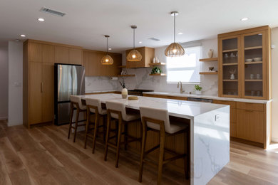 Eat-in kitchen - mid-sized modern laminate floor and brown floor eat-in kitchen idea in Los Angeles with medium tone wood cabinets, quartz countertops, white backsplash, quartz backsplash, stainless steel appliances, an island and white countertops