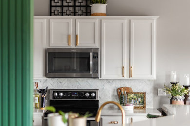 Example of a mid-sized minimalist l-shaped light wood floor, beige floor and vaulted ceiling enclosed kitchen design in Milwaukee with a single-bowl sink, shaker cabinets, white cabinets, quartz countertops, white backsplash, marble backsplash, stainless steel appliances, a peninsula and white countertops