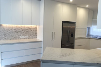Mid-sized contemporary u-shaped eat-in kitchen in Melbourne with an undermount sink, white cabinets, quartz benchtops, stainless steel appliances and vinyl floors.
