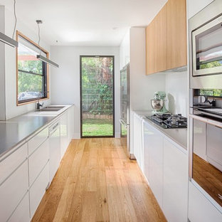 Mid-sized modern kitchen pantry designs - Inspiration for a mid-sized modern galley light wood floor kitchen pantry remodel in Newcastle - Maitland with a double-bowl sink, white backsplash and a peninsula