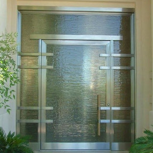 На фото: со средним бюджетом большие входные двери в стиле модернизм с одностворчатой входной дверью, стеклянной входной дверью, бежевыми стенами и полом из травертина