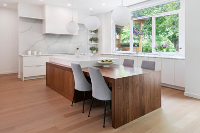Photo of a large modern u-shaped kitchen/diner in Ottawa with a submerged sink, flat-panel cabinets, white cabinets, engineered stone countertops, white splashback, engineered quartz splashback, integrated appliances, light hardwood flooring, an island and white worktops.