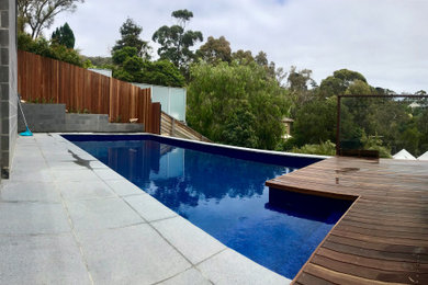Design ideas for a backyard rectangular pool in Melbourne with natural stone pavers.