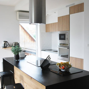 Mid-sized contemporary kitchen pantry pictures - Mid-sized trendy galley medium tone wood floor kitchen pantry photo in Nantes with light wood cabinets, white backsplash, ceramic backsplash, stainless steel appliances and an island