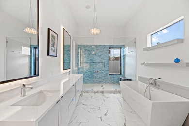 Bild på ett stort funkis vit vitt en-suite badrum, med släta luckor, vita skåp, ett fristående badkar, blå kakel, klinkergolv i keramik, ett integrerad handfat och bänkskiva i kvarts