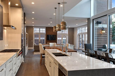 Eat-in kitchen - large transitional u-shaped medium tone wood floor and brown floor eat-in kitchen idea in Chicago with a double-bowl sink, recessed-panel cabinets, light wood cabinets, quartzite countertops, beige backsplash, glass tile backsplash, stainless steel appliances and two islands