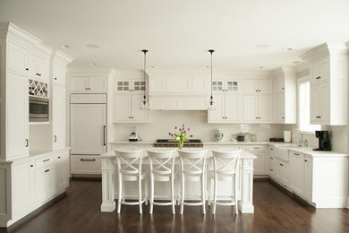 Kitchen - transitional dark wood floor and brown floor kitchen idea in Chicago with a farmhouse sink, shaker cabinets, white cabinets, white backsplash, subway tile backsplash, paneled appliances and an island