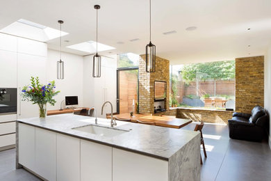 Medium sized scandi single-wall open plan kitchen in London with white cabinets, marble worktops, an island and grey floors.
