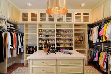 Photo of a large traditional women's dressing room in Sacramento with raised-panel cabinets, beige cabinets and dark hardwood floors.