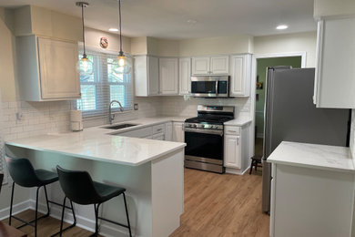 Inspiration for a mid-sized timeless u-shaped medium tone wood floor and brown floor kitchen pantry remodel in DC Metro with an undermount sink, shaker cabinets, white cabinets, quartz countertops, white backsplash, subway tile backsplash, white appliances, a peninsula and white countertops