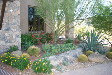 Design ideas for a large mediterranean front yard xeriscape in Phoenix with concrete pavers and a retaining wall.