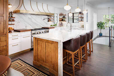 Large transitional l-shaped eat-in kitchen in San Diego with a farmhouse sink, flat-panel cabinets, white cabinets, marble benchtops, white splashback, marble splashback, stainless steel appliances, medium hardwood floors, with island and brown floor.