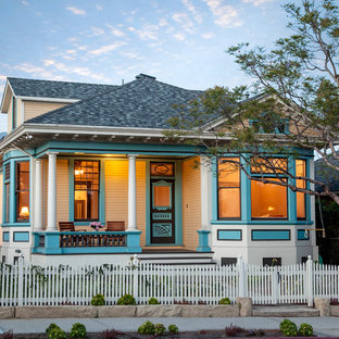 Создайте стильный интерьер: двухэтажный фасад дома среднего размера желтого цвета в викторианском стиле с облицовкой из дерева и вальмовой крышей - последний тренд