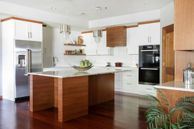 This is an example of a large contemporary l-shaped eat-in kitchen in Other with an undermount sink, shaker cabinets, quartz benchtops, white splashback, porcelain splashback, stainless steel appliances, with island, brown floor, white benchtop, white cabinets and dark hardwood floors.