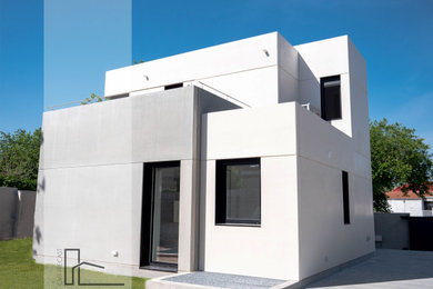 Imagen de fachada de casa blanca y blanca actual de tamaño medio de dos plantas con revestimiento de hormigón, tejado plano, tejado de varios materiales y escaleras