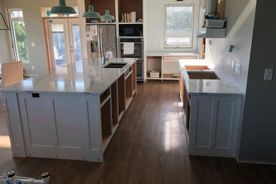 Eat-in kitchen - large country single-wall dark wood floor and brown floor eat-in kitchen idea in Other with an undermount sink, shaker cabinets, white cabinets, quartz countertops, stainless steel appliances, an island and multicolored countertops