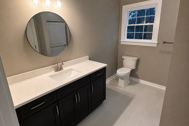 Mid-sized minimalist master ceramic tile and single-sink bathroom photo in Richmond with shaker cabinets, black cabinets, a two-piece toilet, beige walls, an undermount sink, quartzite countertops, a hinged shower door, white countertops and a freestanding vanity