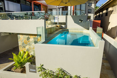 This is an example of a large modern indoor rectangular pool in Cairns with concrete slab.