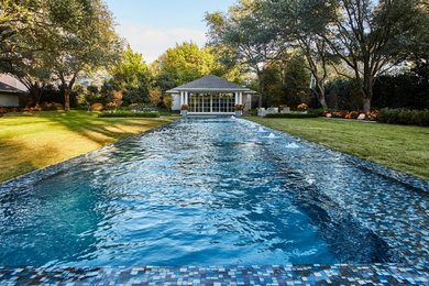 Expansive contemporary backyard rectangular lap pool in Dallas with a pool house and tile.