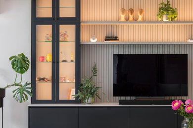 This is an example of a medium sized contemporary open plan living room in Hertfordshire with a built-in media unit and beige floors.
