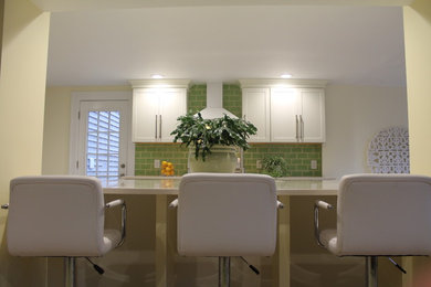 This is an example of a mid-sized contemporary l-shaped eat-in kitchen in New York with an undermount sink, shaker cabinets, white cabinets, quartz benchtops, green splashback, ceramic splashback, white appliances, bamboo floors and with island.