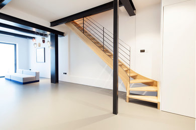 This is an example of a medium sized contemporary fully buried basement in London with white walls and grey floors.