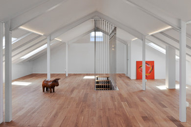 Diseño de sala de estar tipo loft actual grande sin chimenea con paredes blancas, suelo de madera en tonos medios y vigas vistas