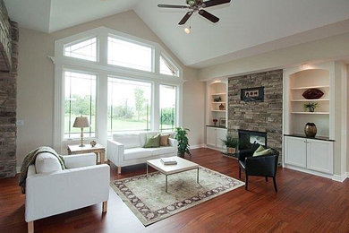 Large trendy open concept medium tone wood floor family room photo in Detroit with beige walls, a standard fireplace, a stone fireplace and no tv