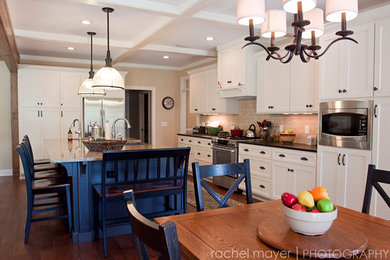 Elegant dark wood floor kitchen photo in Atlanta with a farmhouse sink, shaker cabinets, white cabinets, granite countertops, beige backsplash, stone tile backsplash, stainless steel appliances and an island