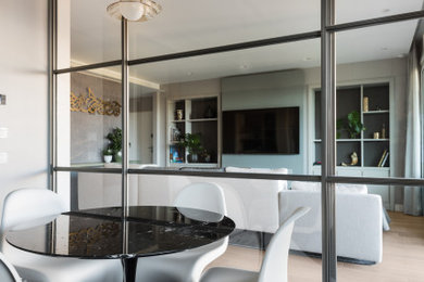 Foto di una grande sala da pranzo aperta verso la cucina minimalista con pareti grigie e parquet chiaro