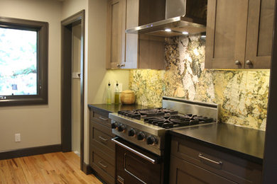 Small elegant galley medium tone wood floor and brown floor enclosed kitchen photo in Detroit with an integrated sink, shaker cabinets, gray cabinets, granite countertops, green backsplash, stone slab backsplash, black appliances and no island