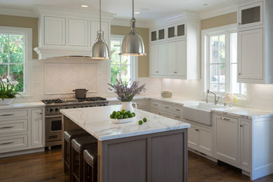 Example of a mid-sized transitional u-shaped dark wood floor open concept kitchen design in San Francisco with a farmhouse sink, recessed-panel cabinets, white cabinets, marble countertops, subway tile backsplash, white appliances, an island and white backsplash