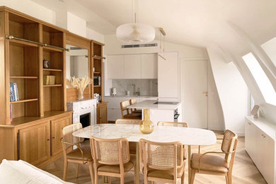 Réalisation d'une salle à manger ouverte sur la cuisine minimaliste de taille moyenne avec un mur blanc, parquet clair, une cheminée standard, un manteau de cheminée en pierre de parement, un plafond voûté et éclairage.