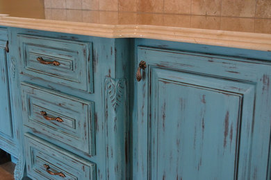 Inspiration for a large mediterranean u-shaped medium tone wood floor eat-in kitchen remodel in Houston with an undermount sink, raised-panel cabinets, distressed cabinets, marble countertops, beige backsplash, stone tile backsplash, stainless steel appliances and an island