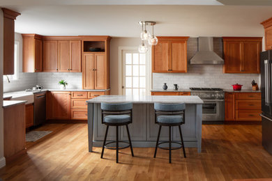 Eat-in kitchen - large transitional u-shaped medium tone wood floor eat-in kitchen idea in Boston with a farmhouse sink, shaker cabinets, light wood cabinets, quartzite countertops, white backsplash, subway tile backsplash, stainless steel appliances and multicolored countertops