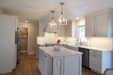 Open concept kitchen - large transitional l-shaped vinyl floor and brown floor open concept kitchen idea in Baltimore with a farmhouse sink, recessed-panel cabinets, white cabinets, quartz countertops, white backsplash, ceramic backsplash, stainless steel appliances, an island and white countertops
