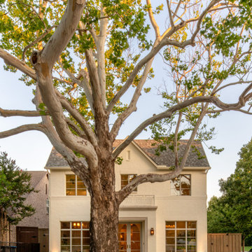 Painted brick European style home framed by a mature