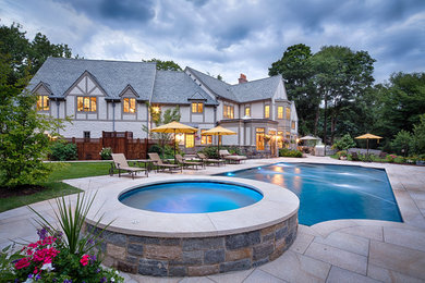Example of a large classic backyard custom-shaped lap hot tub design in New York with decking