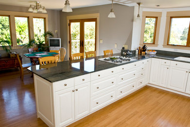 Eat-in kitchen - large traditional u-shaped light wood floor and beige floor eat-in kitchen idea in San Luis Obispo with a double-bowl sink, raised-panel cabinets, white cabinets, a peninsula and black countertops