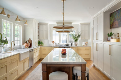 Mid-sized u-shaped light wood floor and brown floor eat-in kitchen photo in Kansas City with a drop-in sink, shaker cabinets, yellow cabinets, quartzite countertops, white backsplash, ceramic backsplash, stainless steel appliances, an island and white countertops