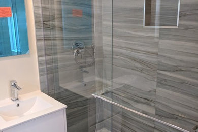 Inspiration for a small contemporary gray tile and porcelain tile dark wood floor and brown floor alcove shower remodel in Miami with flat-panel cabinets, white cabinets, a one-piece toilet, white walls, an integrated sink, quartz countertops, a hinged shower door and white countertops