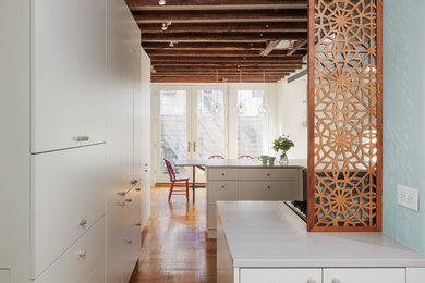 Inspiration for a small contemporary medium tone wood floor and brown floor eat-in kitchen remodel in Philadelphia with flat-panel cabinets, white cabinets, quartz countertops, stainless steel appliances, a peninsula and white countertops