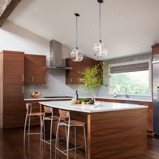 Ejemplo de cocina comedor en L, vintage, extra grande, con fregadero bajoencimera, armarios con paneles lisos, puertas de armario de madera en tonos medios, encimera de mármol, salpicadero verde, salpicadero de azulejos de vidrio, electrodomésticos de acero inoxidable, suelo de madera oscura y una isla