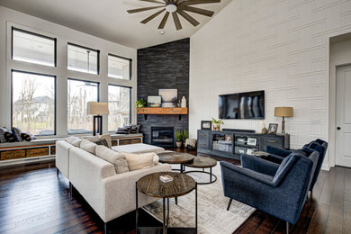 Photo of a mid-sized contemporary enclosed living room in Indianapolis with dark hardwood floors, a corner fireplace, a tile fireplace surround, a wall-mounted tv, multi-coloured walls and beige floor.