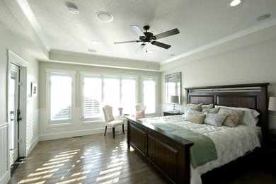 Large traditional master bedroom in Calgary with beige walls, medium hardwood floors, no fireplace and brown floor.