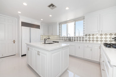 Example of a large minimalist u-shaped porcelain tile and white floor open concept kitchen design in Los Angeles with white cabinets, quartzite countertops, gray backsplash, mosaic tile backsplash, white appliances, an island and white countertops