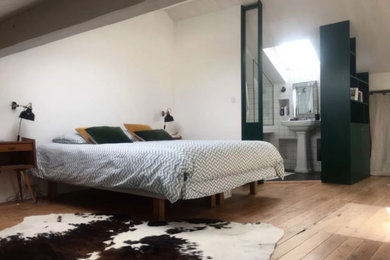 Idée de décoration pour une grande chambre vintage avec parquet clair et poutres apparentes.