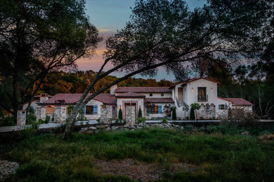 Inspiration for a huge mediterranean white two-story stucco exterior home remodel in Sacramento with a tile roof