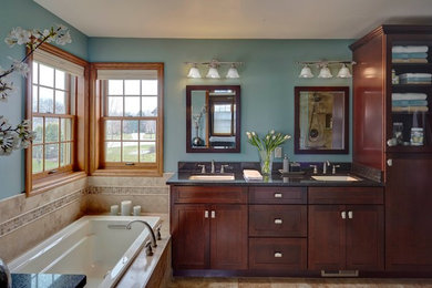 Mid-sized elegant master stone tile and beige tile ceramic tile corner shower photo in Milwaukee with recessed-panel cabinets, dark wood cabinets, blue walls, an undermount sink and quartz countertops