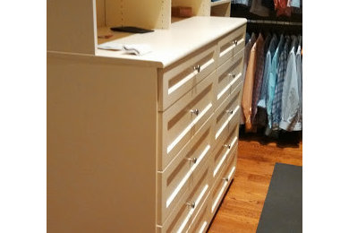 Mid-sized trendy gender-neutral light wood floor walk-in closet photo in Boston with white cabinets